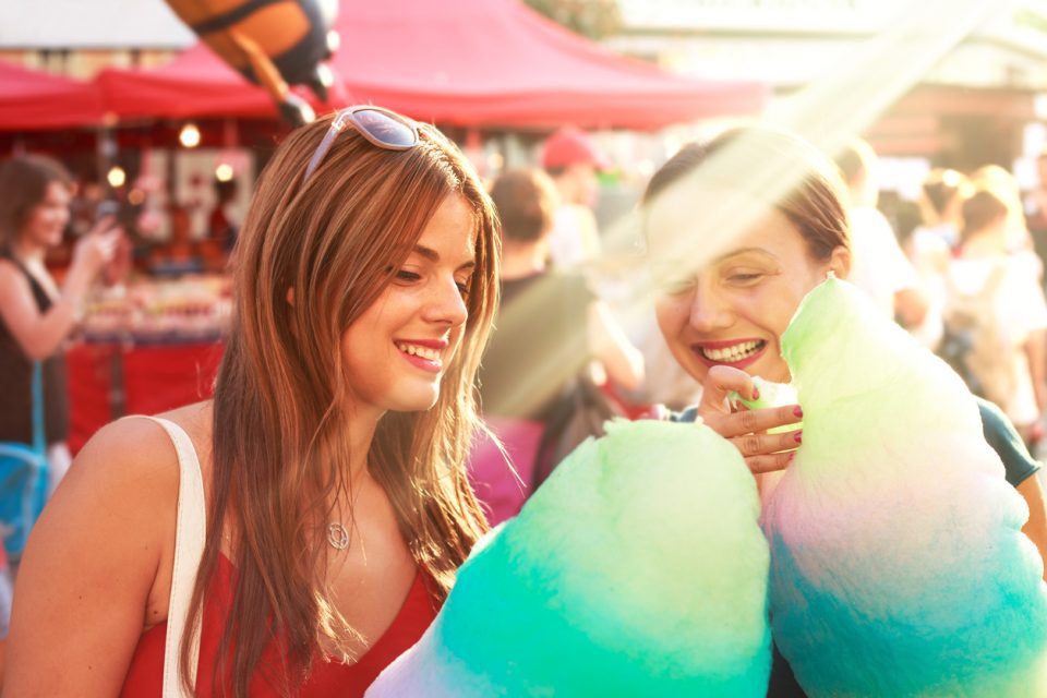 young women eating cotton candy and enjoying a street fair