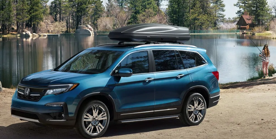 A blue Honda Pilot against a lake.