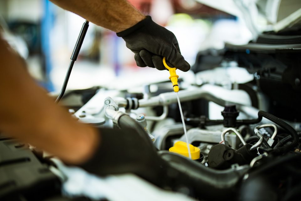 Mechanic examining car oil in a repair shop.