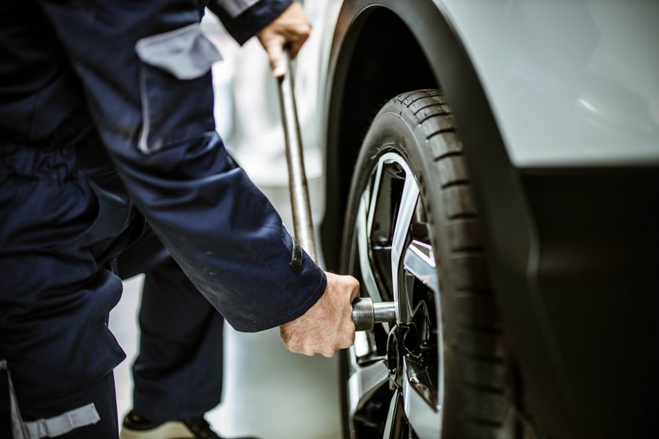 Close up of a repairman changing wheel and tire in a workshop.