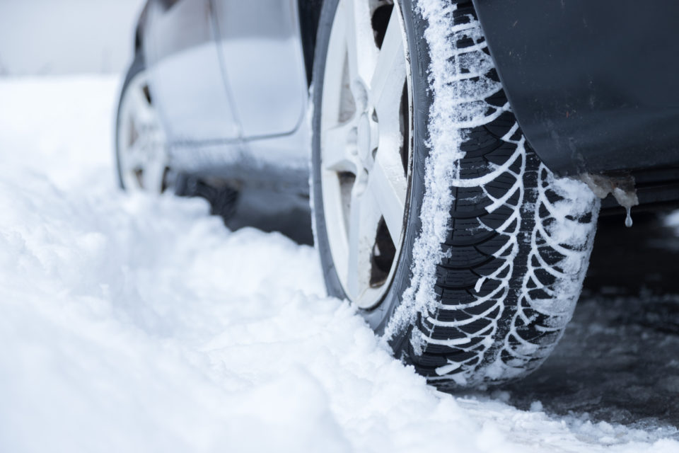 Car tire in winter on the road covered with snow, close up picture