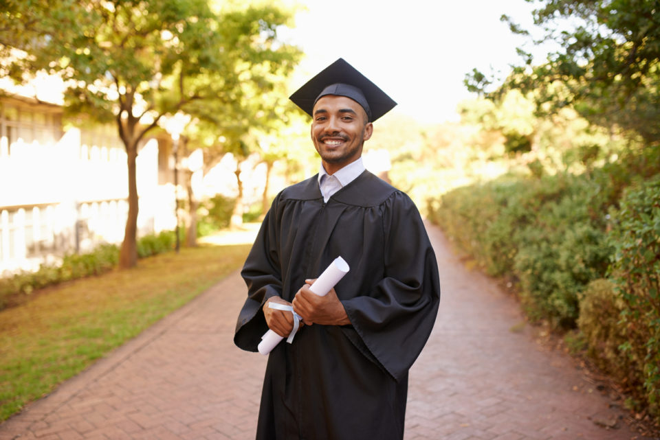 Cropped portrait of a young man posing with his degree on graduation day