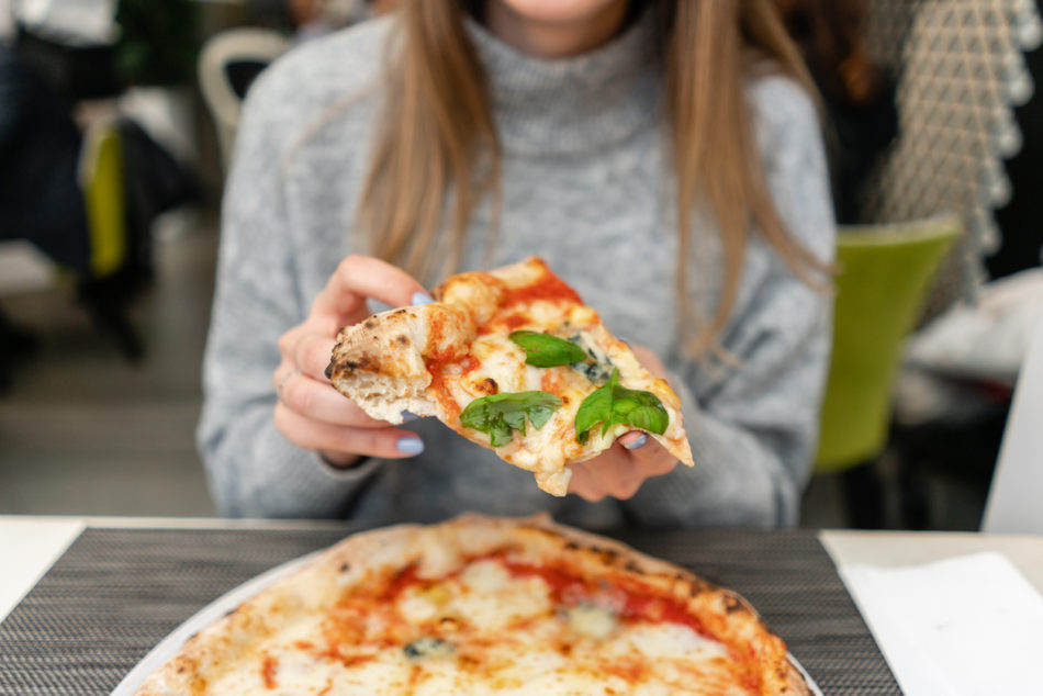 woman eating pizza at a restaurant